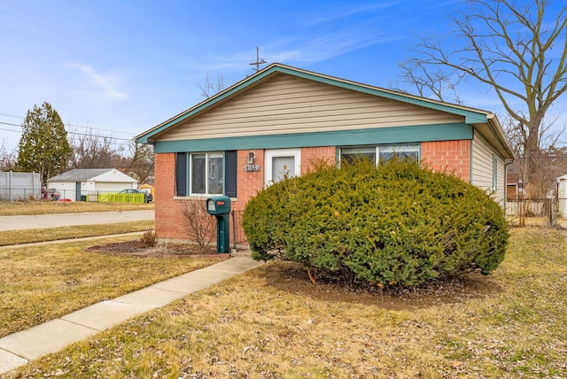 bungalow-style house featuring fence, a front lawn, and brick siding