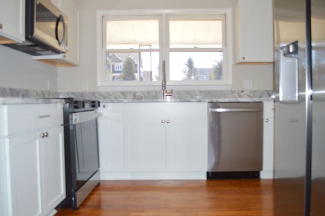 kitchen with stainless steel appliances, light wood finished floors, and white cabinets