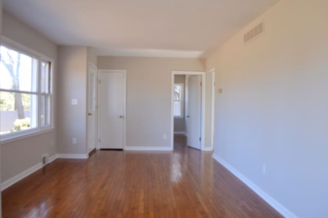 unfurnished room featuring baseboards, visible vents, and dark wood-style flooring