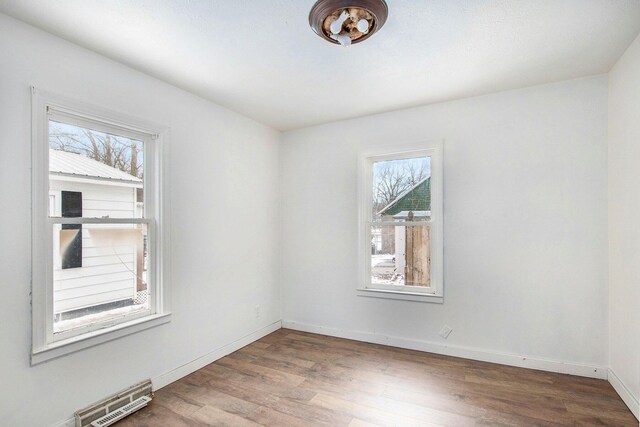 empty room featuring visible vents, baseboards, and wood finished floors