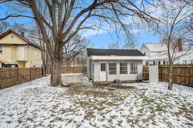 snow covered house featuring an outbuilding and a fenced backyard