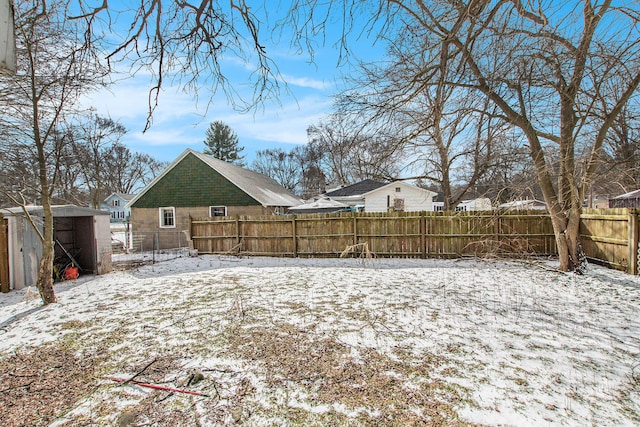 yard layered in snow with an outbuilding, a fenced backyard, and a storage unit