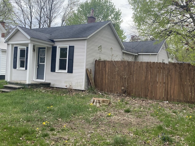 221 James St, Allegan, MI 49010 - view of property exterior with a lawn, roof with shingles, fence, and a chimney