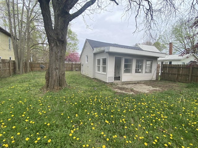221 James St, Allegan, MI 49010 - back of property with a fenced backyard, a yard, and metal roof