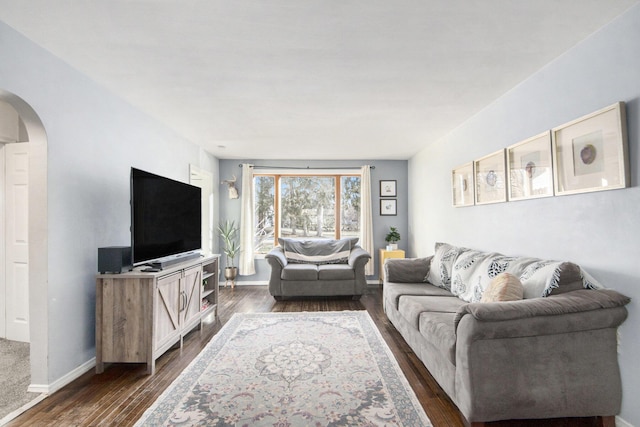 living room with arched walkways, dark wood finished floors, and baseboards