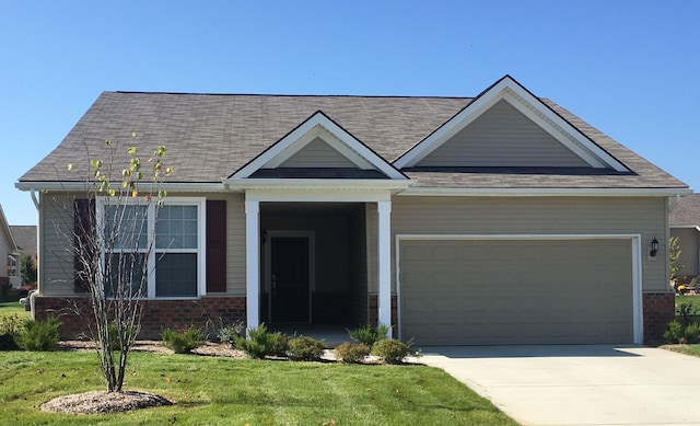 view of front of house with a front yard, brick siding, driveway, and an attached garage