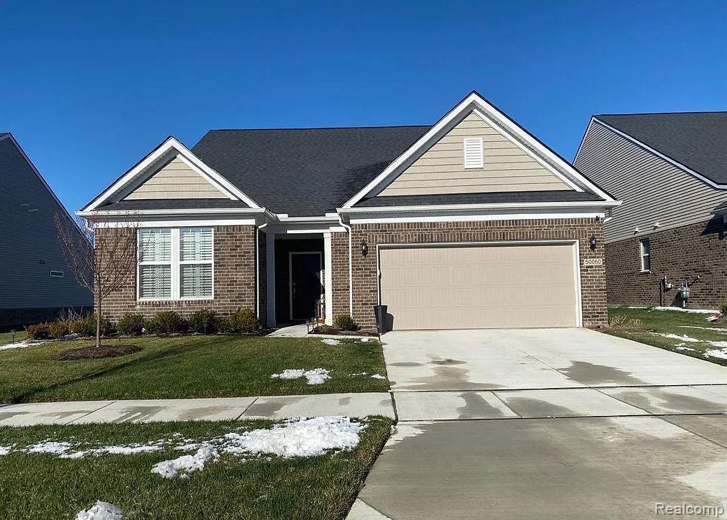3011 Sheffield Cir, Clarkston, MI 48346 - view of front of home featuring brick siding, a garage, driveway, and a front lawn
