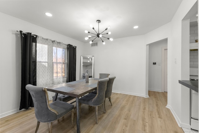 dining area featuring a notable chandelier, light wood-style flooring, baseboards, and visible vents