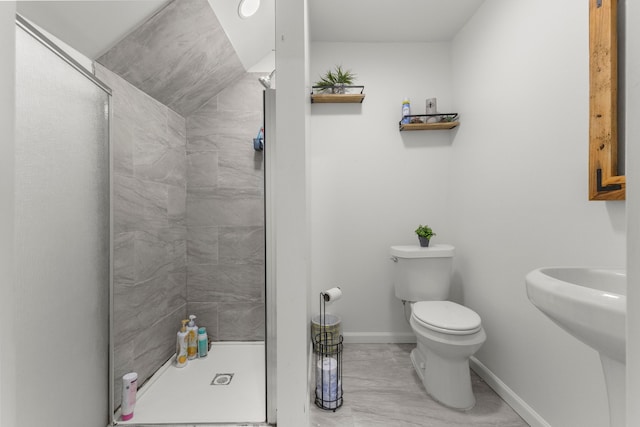 full bathroom featuring a sink, baseboards, toilet, and a stall shower