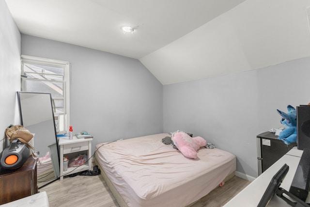 bedroom featuring baseboards, light wood-style flooring, and vaulted ceiling