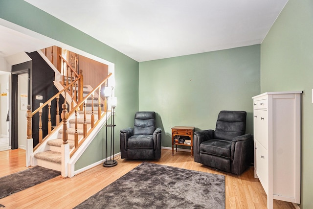 sitting room featuring stairway, baseboards, and wood finished floors