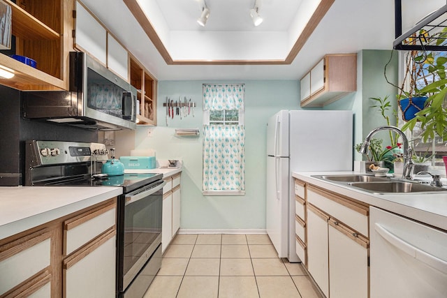 kitchen with a sink, light countertops, appliances with stainless steel finishes, open shelves, and a tray ceiling