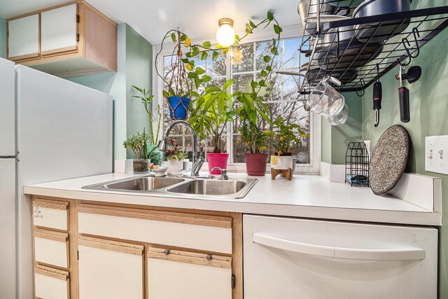 kitchen featuring light countertops, white appliances, and a sink