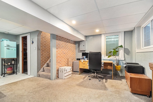 office space with carpet, brick wall, and a drop ceiling