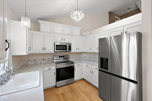 kitchen featuring a chandelier, lofted ceiling, a sink, light countertops, and appliances with stainless steel finishes