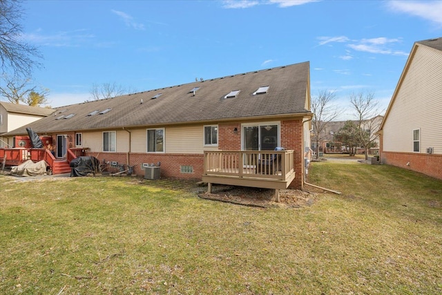 rear view of house featuring a wooden deck, a lawn, and brick siding