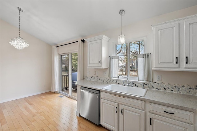 kitchen with pendant lighting, light wood finished floors, white cabinetry, a sink, and dishwasher