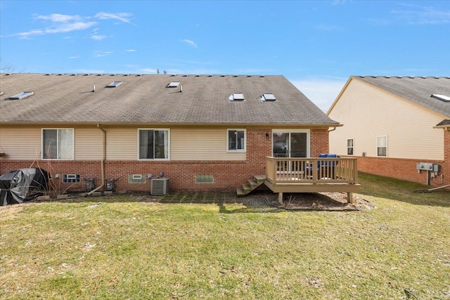 back of house with brick siding, central AC unit, a lawn, and a wooden deck