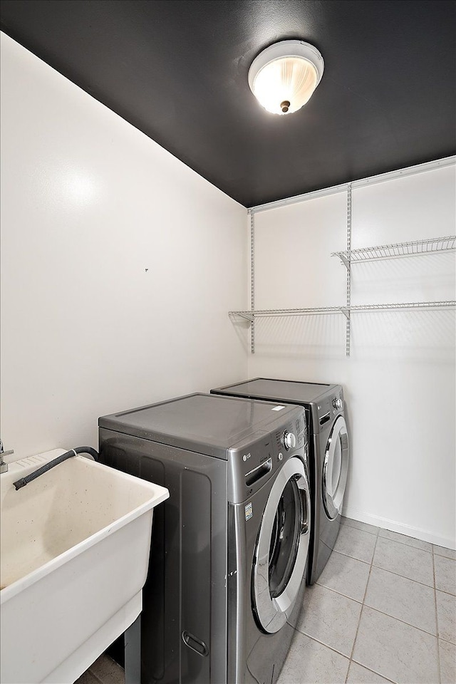 clothes washing area featuring light tile patterned floors, laundry area, a sink, and washer and dryer