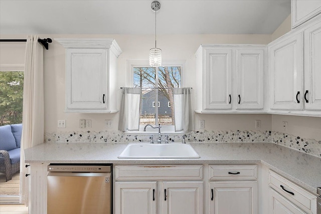 kitchen with light countertops, white cabinets, dishwasher, and a sink