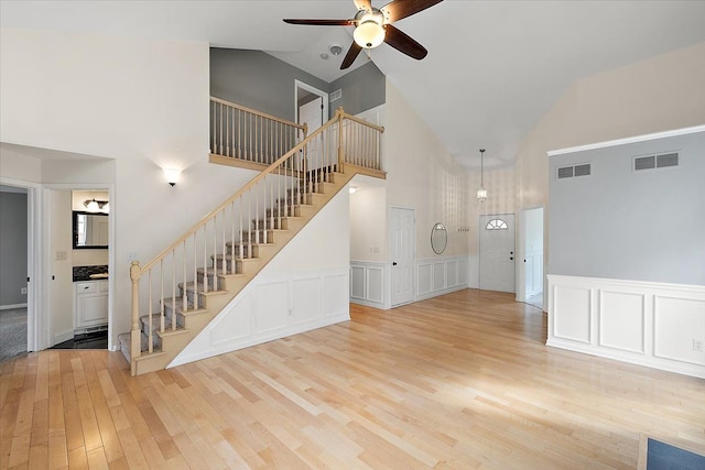 unfurnished living room with light wood-type flooring, visible vents, ceiling fan, and stairs