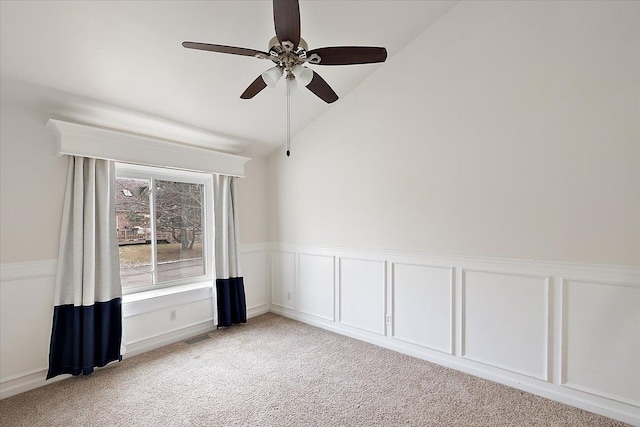 spare room with lofted ceiling, ceiling fan, light colored carpet, a wainscoted wall, and visible vents