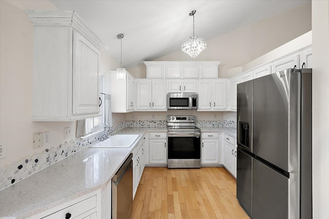 kitchen with pendant lighting, stainless steel appliances, light wood-style flooring, white cabinetry, and a sink