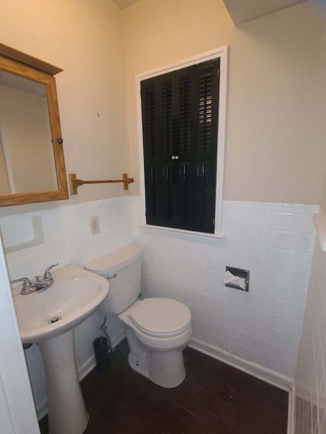 bathroom featuring toilet, tile walls, wood finished floors, and wainscoting