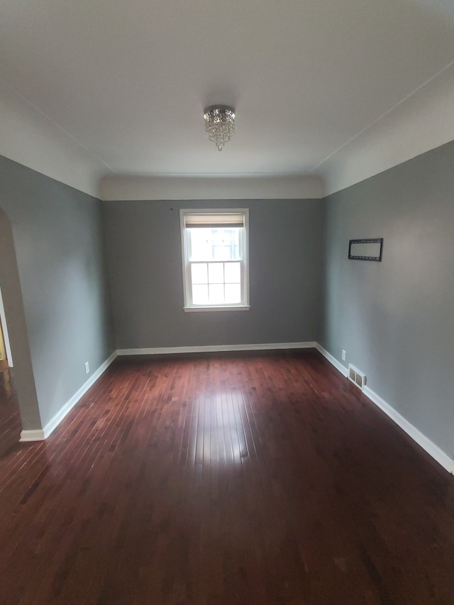 spare room featuring dark wood-style floors, visible vents, and baseboards