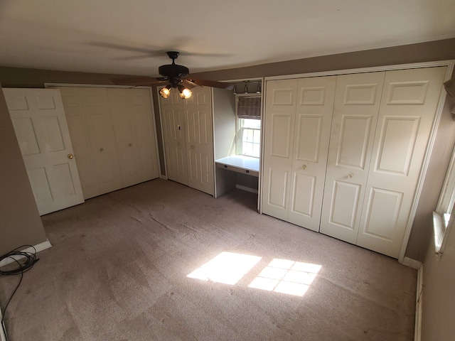 unfurnished bedroom with ceiling fan and two closets