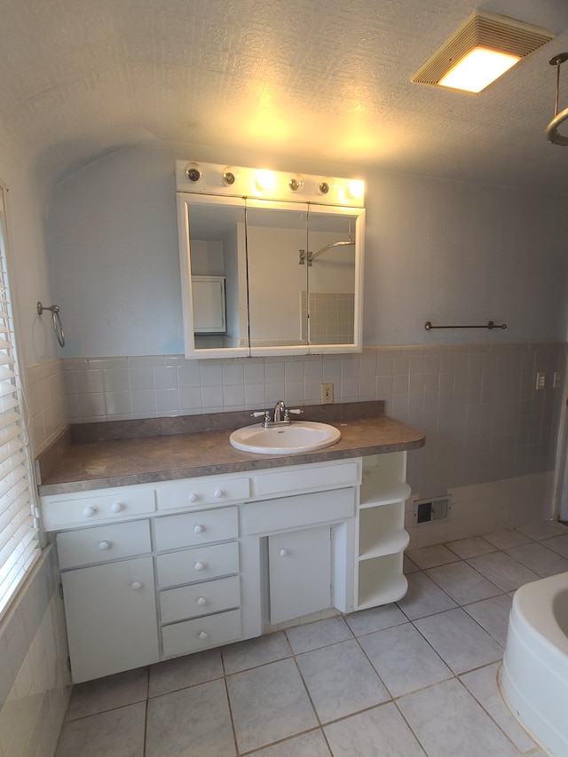 bathroom with visible vents, tile patterned floors, a textured ceiling, vanity, and tile walls