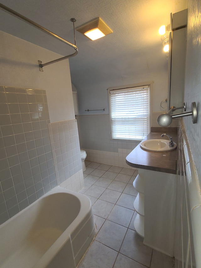 bathroom featuring tile patterned flooring, tile walls, toilet, and vanity