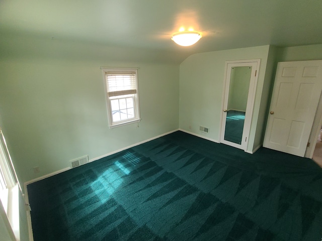 unfurnished bedroom featuring lofted ceiling, baseboards, visible vents, and dark colored carpet