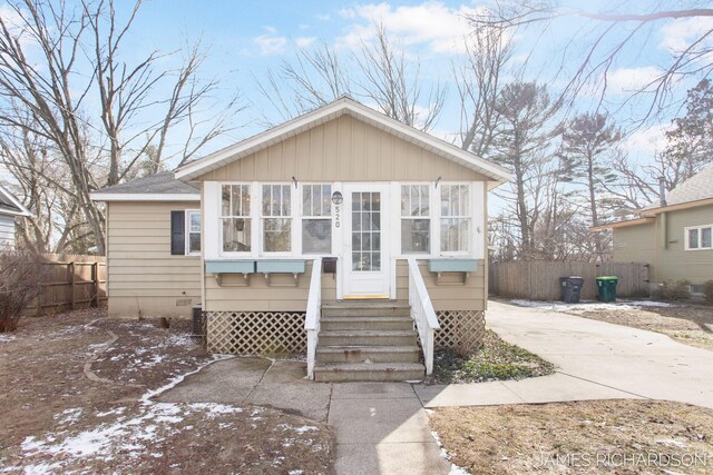 bungalow-style home with a shingled roof, entry steps, crawl space, fence, and driveway