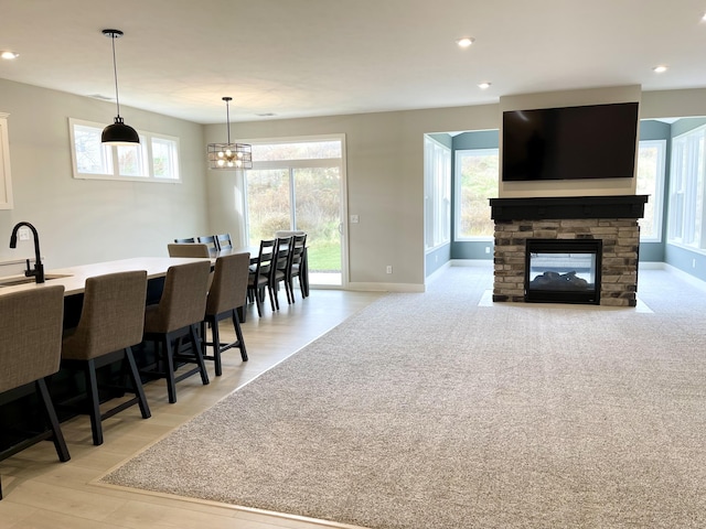 interior space featuring light wood finished floors, recessed lighting, a stone fireplace, a chandelier, and baseboards