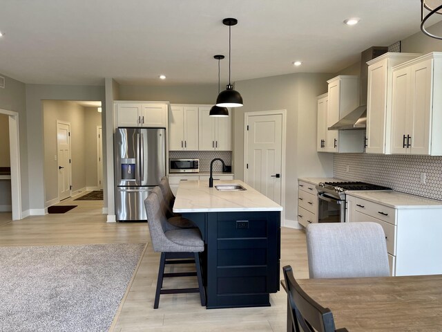 kitchen featuring baseboards, white cabinets, stainless steel appliances, light wood-type flooring, and a sink