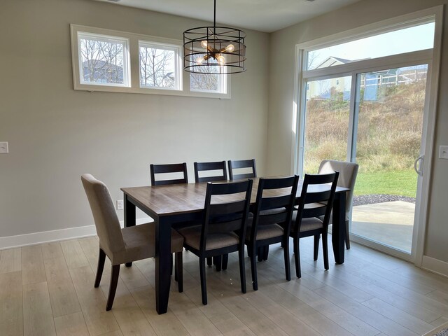 dining room featuring baseboards, a notable chandelier, and light wood-style floors