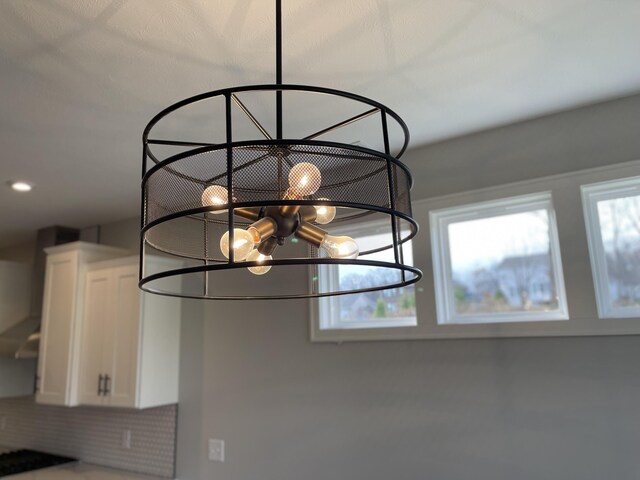 room details featuring a chandelier, recessed lighting, white cabinetry, and wall chimney exhaust hood