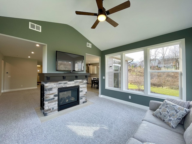 living area with a fireplace, visible vents, vaulted ceiling, and carpet flooring