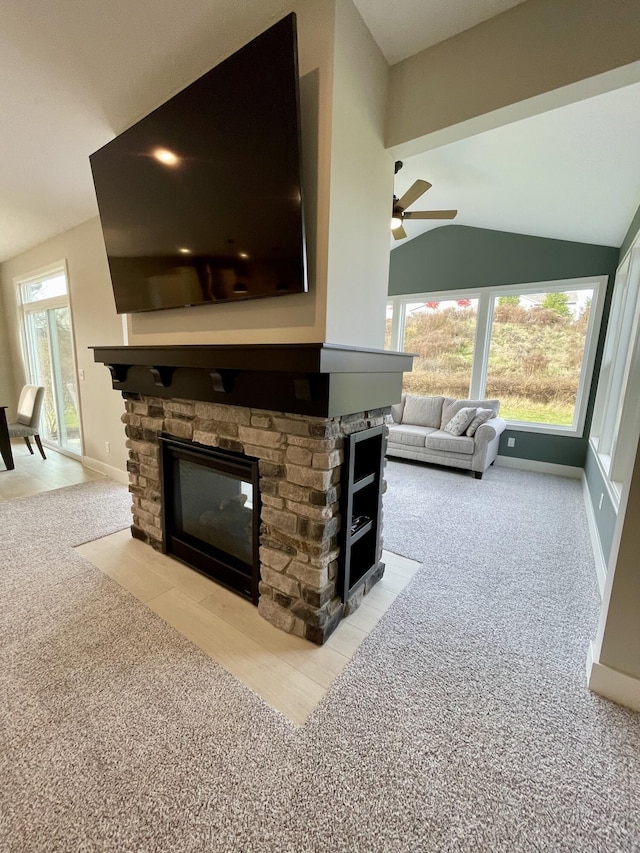 carpeted living room with vaulted ceiling, a fireplace, baseboards, and a healthy amount of sunlight