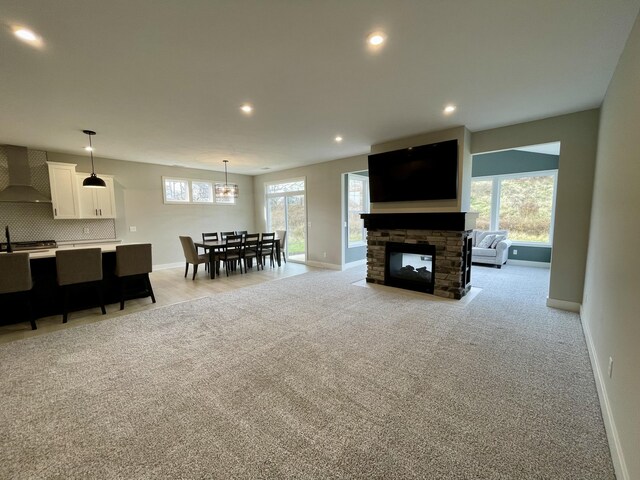 living area featuring baseboards, a stone fireplace, recessed lighting, and light colored carpet