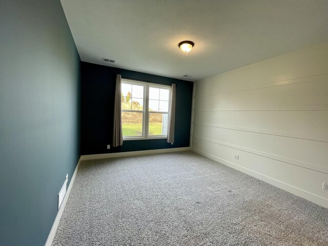 spare room with carpet flooring, visible vents, and baseboards