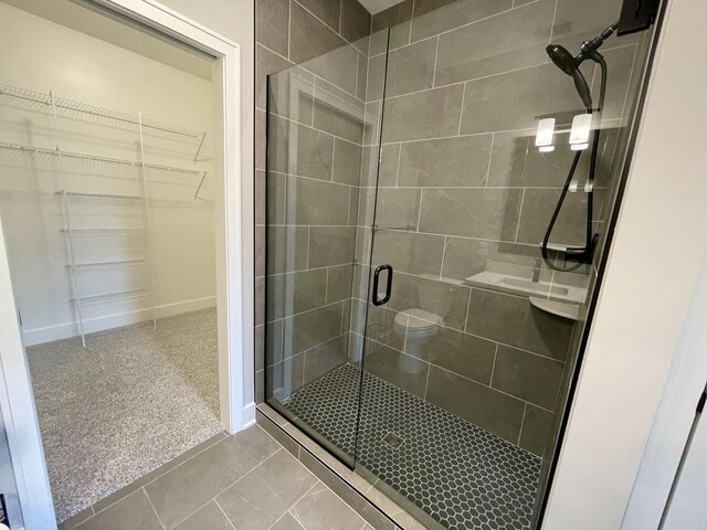 bathroom featuring a stall shower, a spacious closet, and baseboards