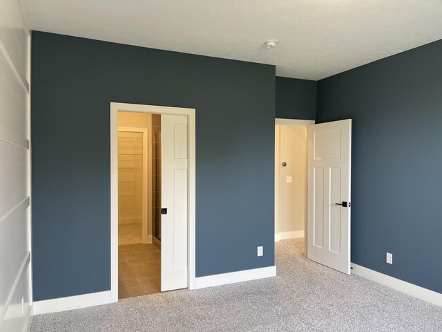 unfurnished bedroom featuring carpet and baseboards