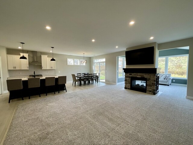 living area featuring recessed lighting, light colored carpet, a fireplace, and baseboards