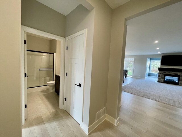 hallway featuring recessed lighting, light carpet, visible vents, baseboards, and light wood-type flooring