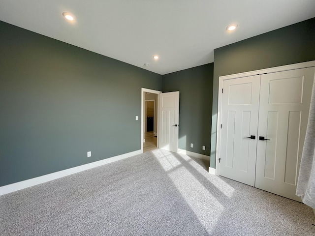 unfurnished bedroom featuring recessed lighting, a closet, light colored carpet, and baseboards