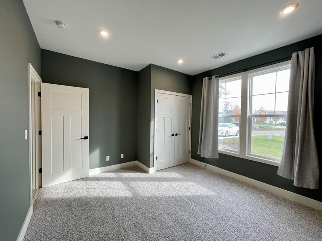 unfurnished bedroom featuring recessed lighting, visible vents, light carpet, and baseboards