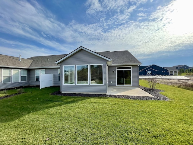 back of house featuring a shingled roof, a patio, and a lawn