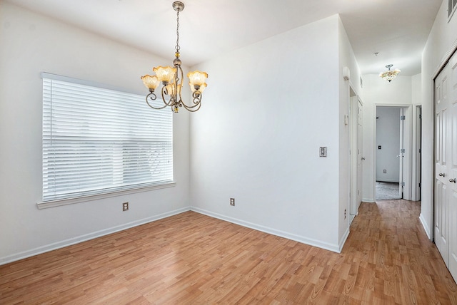 spare room featuring visible vents, baseboards, light wood-type flooring, and an inviting chandelier